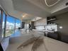 Kitchen featuring a waterfall-edge island with stone-finish countertop, flat-panel cabinetry, open shelving, integrated stainless steel appliances, an