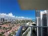Private balcony featuring a glass-panel railing and panoramic coastal and urban scenery
