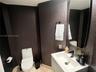 Modern floating vanity with a white integrated basin, matte black widespread faucet, textured wall covering, and a vertical rectangular mirror
