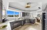 Kitchen featuring dark-finish cabinetry, stone-style countertops, stainless steel appliances, tray ceiling with integrated light fixture, and expansiv
