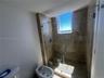 Walk-in shower featuring tile surround, glass enclosure, and built-in bench, complemented by a bidet and natural light from an integrated window
