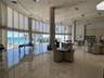 Expansive common area featuring floor-to-ceiling windows, polished stone flooring, structural columns, and spherical pendant lighting, with direct exp
