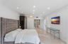 Spacious room featuring polished stone flooring, recessed ceiling lighting, a dark finish built-in wardrobe, and a white architectural door