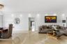 Open-concept interior featuring large-format polished flooring, recessed ceiling lighting, a crystal flush-mount light fixture, and a circular wall mi