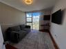 Floor-to-ceiling windows featuring urban scenery, built-in corner desk with integrated shelving, wood-finish flooring, and circular flush-mount ceilin