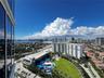 High-rise perspective featuring glass curtain wall facade, expansive green space with mature palms, and structured recreation area with shade sails