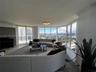 Floor-to-ceiling panoramic windows, sliding glass doors, neutral tile flooring, and crown molding