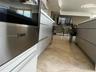 Kitchen featuring stainless steel Bosch wall oven, flat-panel cabinetry, stone-finish countertops, and tile flooring
