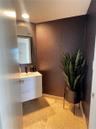 Modern white floating vanity featuring dual handleless drawers, integrated rectangular sink basin, and dark faucet hardware, complemented by textured 