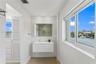 Floating vanity with integrated sink, recessed lighting, mirrored medicine cabinet, louvered-door cabinetry, and window with water frontage