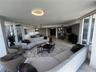 Open-concept living area featuring stone-finish flooring, floor-to-ceiling glass panel doors, custom recessed ceiling lighting, and minimalist built-i