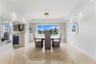 Dining area featuring polished stone flooring, recessed lighting, a crystal flush-mount ceiling fixture, and a large window with water scenery