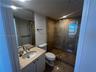 Bathroom featuring a stone-surface vanity with an integrated basin, large wall-mounted mirror, and a walk-in shower with stone tile surround and glass
