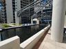 Rectangular reflective pool with built-in water features, architectural overhead metal framing, cylindrical support columns, and light-toned stone til