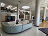 Spacious common area featuring large structural columns, polished stone flooring, intricate laser-cut wood privacy screens, and overhead geometric lig