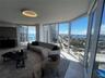 Floor-to-ceiling glass walls, wrap-around windows, stone flooring, minimalist circular ceiling fixture, and a glass-railed balcony