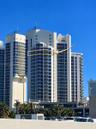 High-rise building featuring white concrete cladding, floor-to-ceiling glass windows, and private balconies