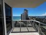 Private balcony featuring stone flooring, a white metal railing with glass panels, and sliding glass doors