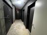 Stone tile flooring, geometric textured wall covering, double-door entry with metallic hardware, dual elevator access, and monochromatic architectural