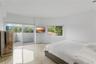 Polished concrete flooring, sliding glass door with access to a private balcony, and dual windows with exterior greenery
