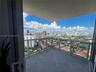 Private balcony featuring stone tile flooring and glass railings, overlooking a panoramic cityscape