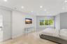 Neutral-toned interior featuring polished flooring, recessed lighting, and large windows with outdoor greenery