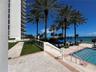 Outdoor swimming pool with tile decking, manicured lawn, palm trees, and barrier railing