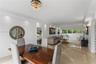 Open-concept living space featuring high-gloss flooring, recessed lighting, a decorative tiered chandelier, and expansive windows