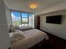 Floor-to-ceiling windows featuring urban scenery, dark wood-finish flooring, recessed ceiling lighting, and a built-in walk-in closet