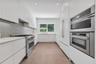 Kitchen featuring flat-panel cabinetry, stainless steel double wall ovens, a gas range, a hexagonal-pattern backsplash, and tile flooring