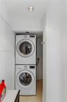 Stackable white front-load washer and dryer unit with recessed ceiling lighting
