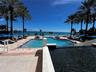 Outdoor pool area featuring a multi-level swimming pool, expansive stone-paver decking, integrated stairs with white metal handrails, and surrounding 