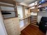 Built-in light wood cabinetry featuring multi-level shelving, hanging rods, and a five-drawer stack, finished with wood-finish flooring