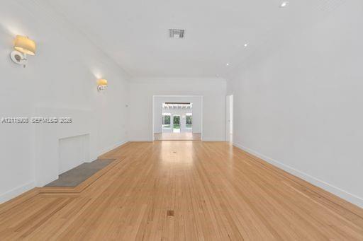 Open-concept interior featuring light wood-finish flooring, a neutral color palette, recessed lighting, wall-mounted light fixtures, and a decorative 