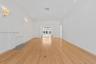 Open-concept interior featuring light wood-finish flooring, a neutral color palette, recessed lighting, wall-mounted light fixtures, and a decorative 