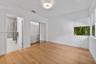 Room featuring wood-finish flooring, a decorative flush-mount ceiling light, a built-in closet with sliding mirrored doors, and window treatments
