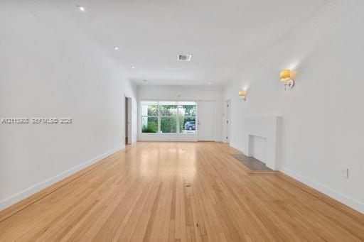 Interior space featuring wood-finish flooring, recessed lighting, wall-mounted light fixtures, and a decorative fireplace surround