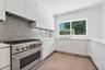 Modern kitchen featuring flat-panel cabinetry, a professional-grade stainless steel range, hexagonal tile backsplash, light-toned stone countertops, a