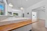 Kitchen featuring a waterfall-edge countertop, butcher block peninsula, geometric tiled backsplash, recessed lighting, and stainless steel built-in do