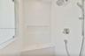 Walk-in shower featuring white subway-style wall tile, a stone-finish bench seat, an integrated wall niche, and dual-function polished chrome shower f