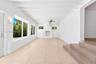 Vaulted ceiling with exposed white beams, large-format tile flooring, brick-surround fireplace, and multiple windows