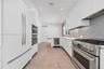 Contemporary kitchen featuring flat-panel white cabinetry, stainless steel professional-grade range, hexagonal tile backsplash, built-in wine refriger