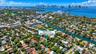 Aerial perspective of a residential property situated in a coastal environment featuring dense mature canopy, proximity to a waterway, and a coastal c