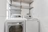 Laundry area featuring wall-mounted wire shelving, two pull-out metal storage baskets, and high-capacity laundry appliances