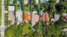 Aerial perspective featuring a lot with mature landscaping, an expansive rear lawn, and a multi-pitched roofline