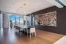 Floor-to-ceiling windows, wood-finish flooring, built-in recessed cabinetry featuring a contrasting stone backsplash, and multi-tier geometric pendant
