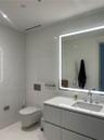 Wall-mounted toilet with a dual-flush actuator plate, large-format tile wall cladding, modern floating vanity with a seamless countertop, rectangular 