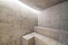 Steam room featuring tiered stone bench seating, full-height wall tiling in a mosaic pattern, large-format stone floor and wall tiles, and integrated 