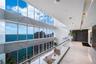 Double-height floor-to-ceiling windows featuring large-format stone wall cladding, glass balcony railing, polished stone flooring, and recessed ceilin