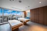 Floor-to-ceiling windows, vertical wood-slat wall paneling, stone tile flooring, and integrated ceiling lighting